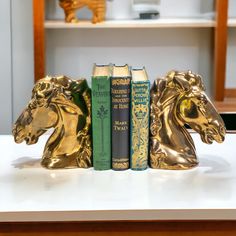 three books are stacked on top of each other in front of a gold horse statue