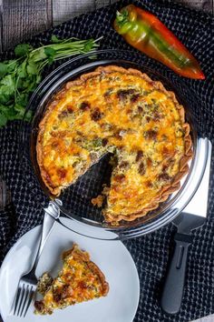 a quiche on a plate with a slice missing from it next to a knife and fork