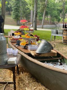 a boat filled with lots of food sitting on top of dry grass next to a picnic table