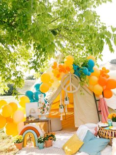 a tent set up with balloons and other decorations on the ground in front of it