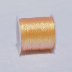 an orange spool of thread sitting on top of a white surface