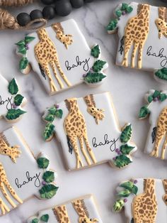 baby shower cookies decorated with giraffes and leaves on a white tablecloth