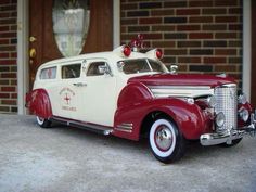 an old fashioned red and white car parked in front of a brick building