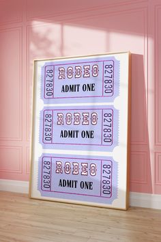 two tickets sitting on top of a wooden floor in front of a pink painted wall