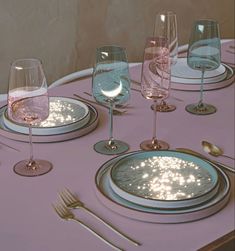 the table is set with wine glasses, plates and utensils