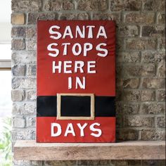 there is a sign that says santa stops here in days on the brick wall next to a window