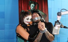 a man and woman are posing for a photo in front of a microphone with their faces painted