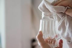 a person holding a glass jar with water in it and cloth on the back of it