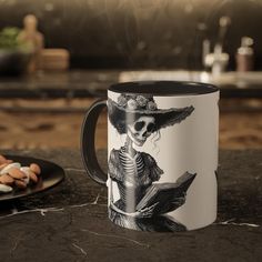 a black and white coffee mug sitting on top of a counter next to a plate with cookies