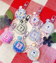 several keychains on a red and white checkered table cloth with flowers in the background