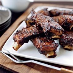 some meat is on a white plate with silverware