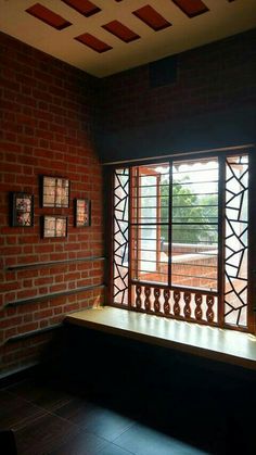 an empty bench in front of a brick wall and window with wooden slats on it