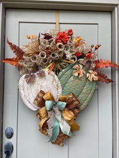 a wreath hanging on the front door of a house decorated with autumn leaves and flowers