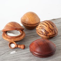 three wooden containers with salt in them sitting on a table next to an egg shell