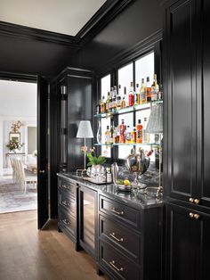 a black kitchen with lots of bottles on the shelves