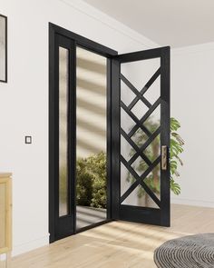 an open black door in the middle of a room with wood flooring and white walls