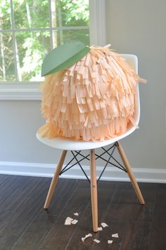 a chair made out of pieces of paper on top of a hard wood floor next to a window