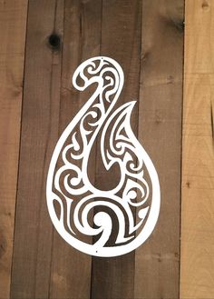 an intricately designed paper cut out of wood on a wooden background with the letter s