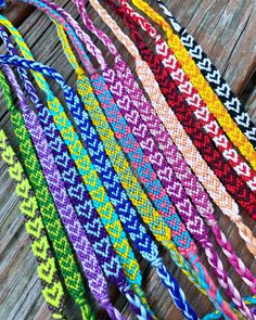 several different colored braided bracelets on wooden surface