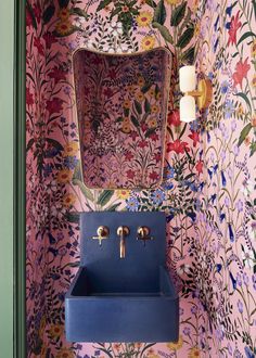 a blue sink sitting under a mirror next to a wall mounted faucet in a bathroom