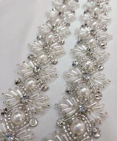 the beaded necklace is made with pearls and swarong crystals on white fabric