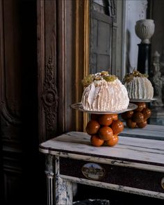 a cake sitting on top of a wooden table next to oranges and a mirror