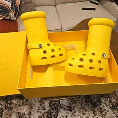 a pair of yellow rain boots sitting in a box on top of a table next to a couch