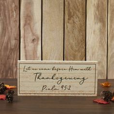 a wooden sign sitting on top of a table next to autumn leaves and dry flowers