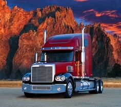 a red semi truck parked in front of a mountain range at sunset with the sun setting