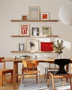 a dining room table with chairs and pictures on the wall above it, along with other furniture