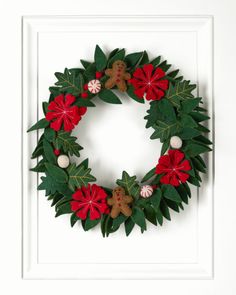 a christmas wreath with poinsettis and holly leaves on a white door frame