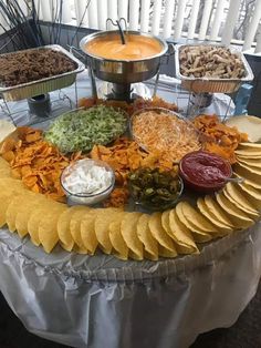 a platter filled with chips and dips on top of a white table cloth