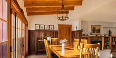 a dining room table and chairs with wood trim around the edges, in front of an open bookcase