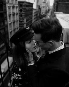 black and white photograph of a man kissing a woman's forehead on the street