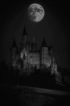 an old castle lit up at night with the moon in the background