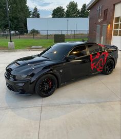 a black sports car parked in front of a building with red graffiti on the side