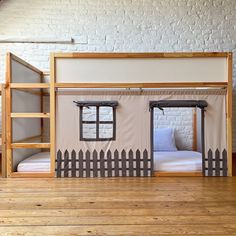 a bunk bed with two sets of windows on the top and bottom, in front of a white brick wall