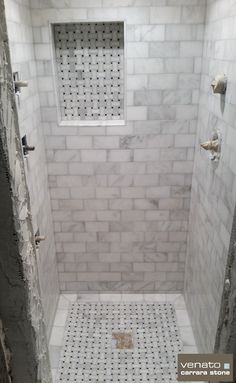 a walk in shower sitting next to a white tiled wall and floor covered in gray grout