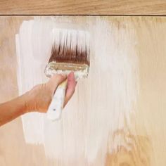 a person with a paintbrush painting a wooden surface