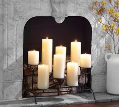 a bunch of white candles sitting on top of a mantle next to a vase with yellow flowers