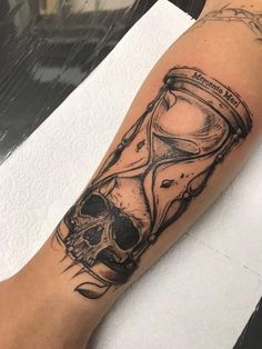 a skull and hourglass tattoo on the arm