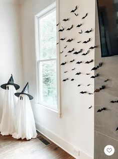 two halloween decorations in the corner of a room with a tv and bats on the wall