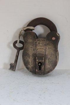 an old padlock with a key hanging from it's side on a white wall