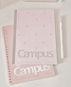 a pink notebook and pen sitting on top of a white desk