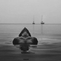 a person floating in the water with boats in the background