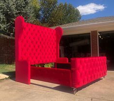 a red couch sitting in the middle of a driveway