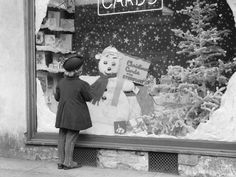 a little boy standing in front of a store window with a snowman on it