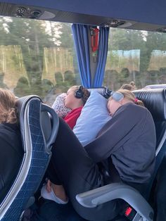 two people sleeping on the back of a bus with their heads resting on each other