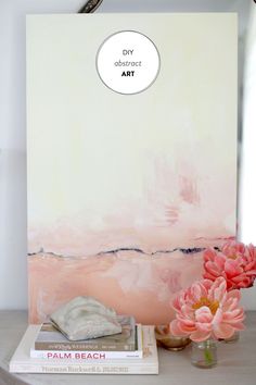 pink flowers are sitting on a table next to a painting