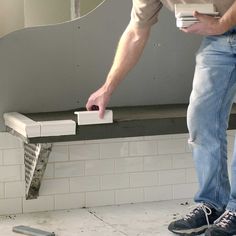 a man standing on top of a bathroom floor next to a mirror and tiled wall